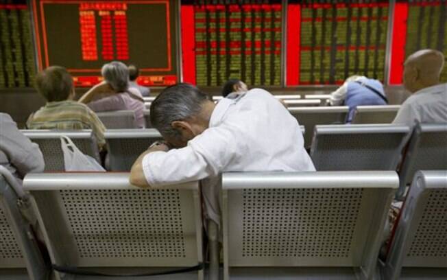 Investidores chineses monitorar os preços das ações em uma casa de corretagem em Pequim