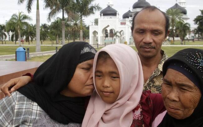 Jamaliah, à esq., beija a filha Raudhatul Jannah, 14, que reencontrou após dez anos. A menina sumiu durante o tsunami de 2004, em Banda Aceh (8/08). Foto: Reuters