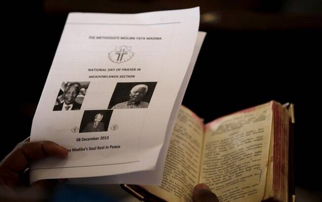 Mulher segura bíblia e programação durante serviço religioso em Soweto (8/12)