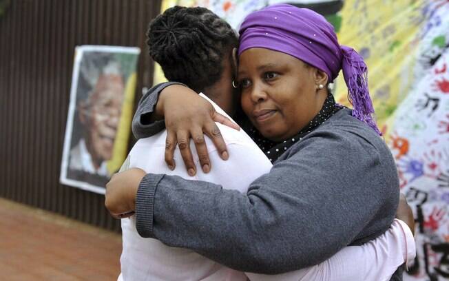 Mulheres se abraçam e se consolam em Soweto. O ex-presidente morou na região (6/12)