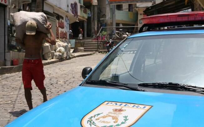 Morador passa perto de carro da PM no acesso à favela