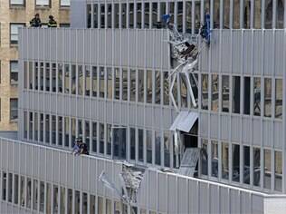 Bombeiros examinam danos causados à fachada do edifício por acidente com guindaste