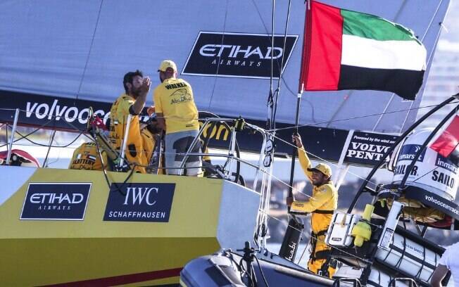 Integrante da tripulação do Abu Dhabi exibe a bandeira dos Emirados Árabes na chegada à Cidade do Cabo