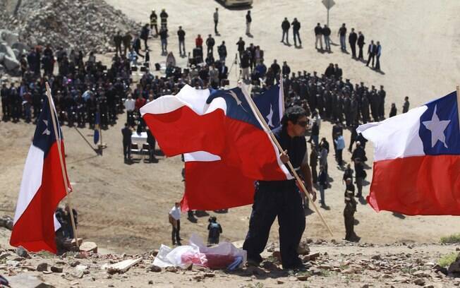 Homem coloca bandeiras do Chile na entrada da mina San José, onde autoridades marcaram um ano do resgate (13/10/2011)