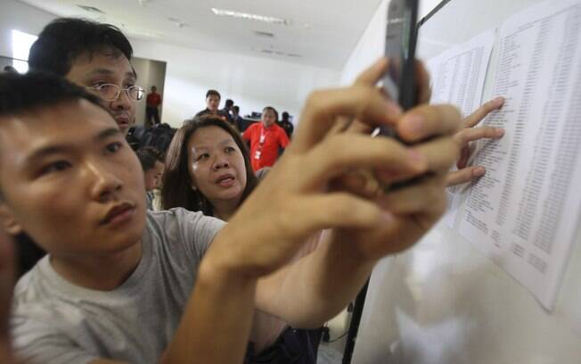 Familiares conferem lista com nomes dos tripulantes e passageiros do voo da AirAsia desaparecido. Foto: AP Photo/Trisnadi
