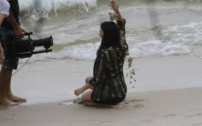 Tatá Werneck rola na areia durante gravação na praia
