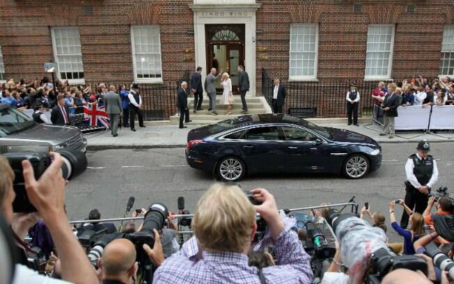 Fotógrafos e curiosos observam Charles e Camila entrarem na maternidade, enquanto aguardam saída de Kate e o bebê