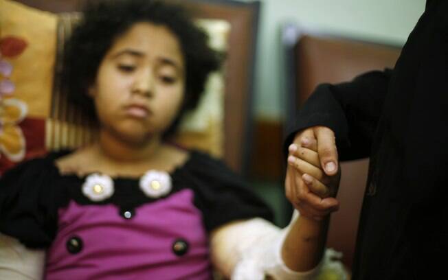A tia da palestina Yasmin al-Bakri, 11, a quem médicos disseram ter sido ferida em ataque aéreo israelense, segura a mão da  sobrinha em hospital de Gaza (6/08)