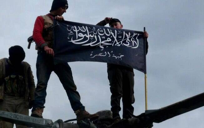 Rebeldes da Frente al-Nusra, afiliada à Al-Qaeda, seguram sua bandeira no topo de helicóptero da Força Aérea da Síria na base de Taftanaz (11/01)