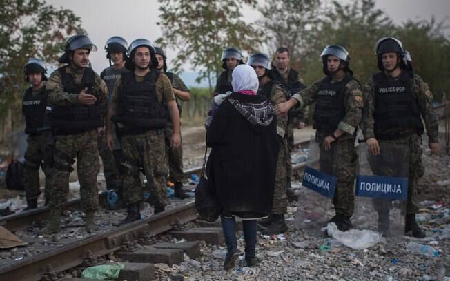 Policiais macedônios protegem a fronteira enquanto permitem que mãe síria e seu bebê atravessem da Grécia para a Macedônia (25/08)