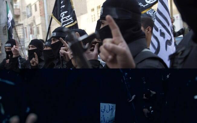 Membros de grupo islâmico seguram armas durante protesto contra regime em Deir el-Zor (25/02)