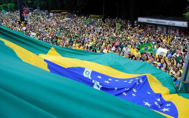 Manifestantes erguem bandeira do Brasil durante o maior ato da história do País, em São Paulo