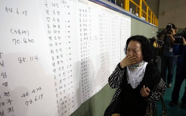 Mulher se emociona ao ver o nome do filho em lista de sobreviventes na academia para onde eles foram levados, na Coreia do Sul (16/04)