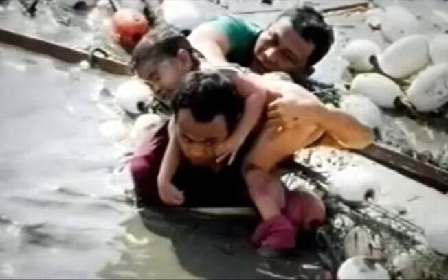 Homem ajuda criança a sair de local alagado após tsunami da Indonésia (arquivo). Foto: Reprodução/Youtube