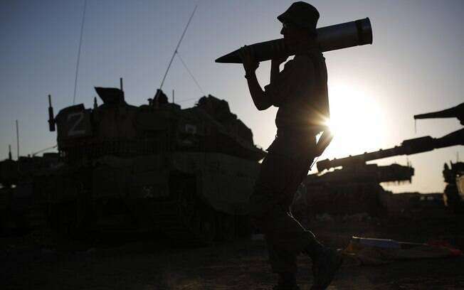 Soldado israelense carrega projétel perto da fronteira com a Faixa de Gaza (7/08)