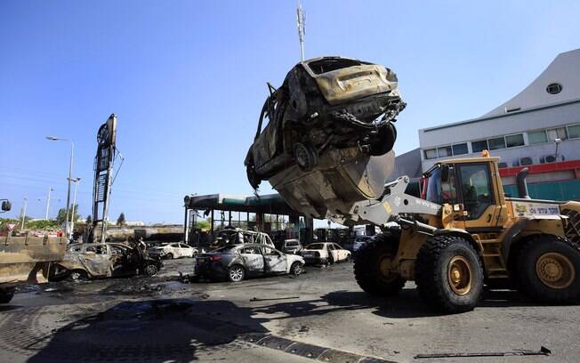 Carros destruídos são removidos de posto de gasolina na cidade de Ashdod, Israel, que foi atingido por foguete lançado da Faixa de Gaza