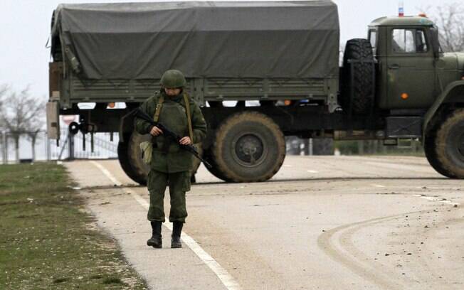 Homem armado não identificado com uniforme de camuflagem bloqueia estrada que leva a aeroporto militar em Sevastopol, na Crimeia