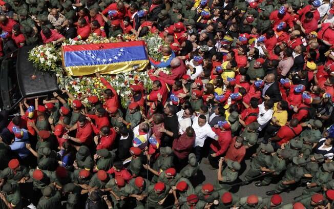 Pessoas caminham ao lado de caixão de Hugo Chávez coberto com bandeira venezuelana em Caracas (06/03)