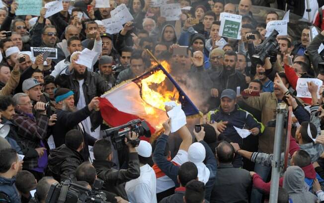Ativistas queimam uma representação de bandeira francesa durante protesto contra charges publicadas pelo Charlie Hebdo em Argel, Argélia