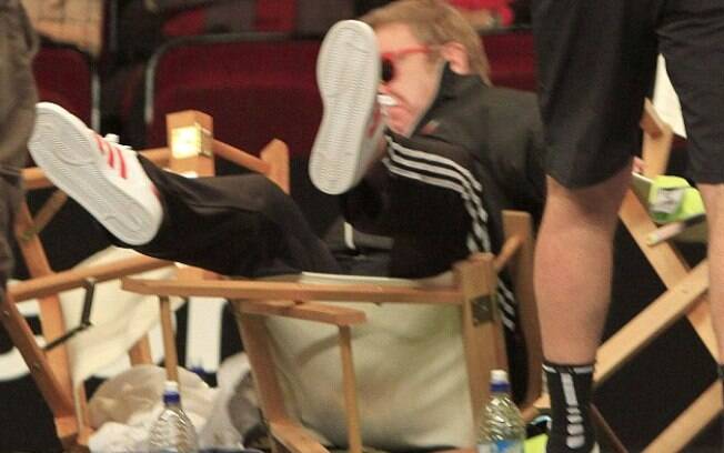 Elton John cai da cadeira em torneio de tênis
