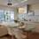 A bancada de Corian e a mesa de vidro separam a cozinha da sala de estar. Ao fundo, o micro-ondas ao lado do fogão. Foto: Divulgação