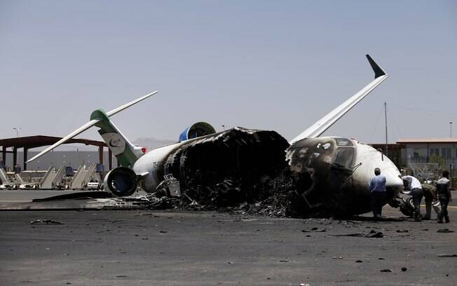 Funcionários de Felix Airways, companhia aérea doméstica, inspecionam avião destruído por ataques aéreos liderados pela Arábia Saudita no aeroporto internacional de Sanaa