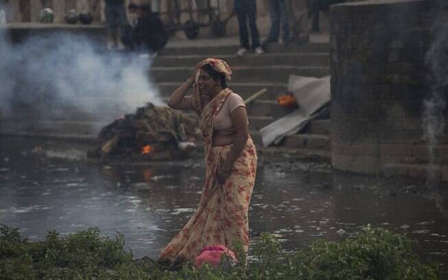 Mulher chora ao lado de local em que corpo de vítima é cremado no meio da rua