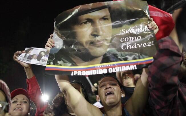 Partidários de Hugo Chávez seguram cartaz em que se leem 'Sejamos como Chávez' e 'Proibido esquecer' durante homenagem a líder venezuelano, morto nesta terça, em Caracas (05/03)