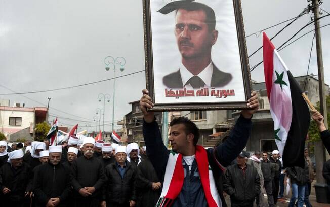 Druso carrega retrato do presidente sírio em que se lê 'Síria, Deus protege você', nas, Colinas do Golan (17/04)