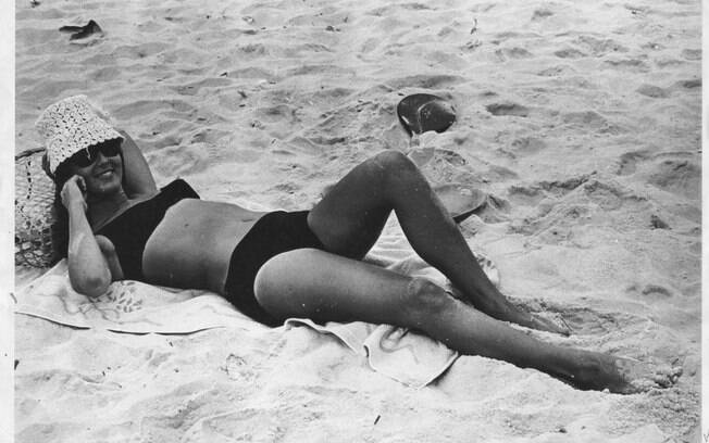 Helô Pinheiro, aos 17 anos, na praia de Ipanema: biquini, toalha e chapéu de palha