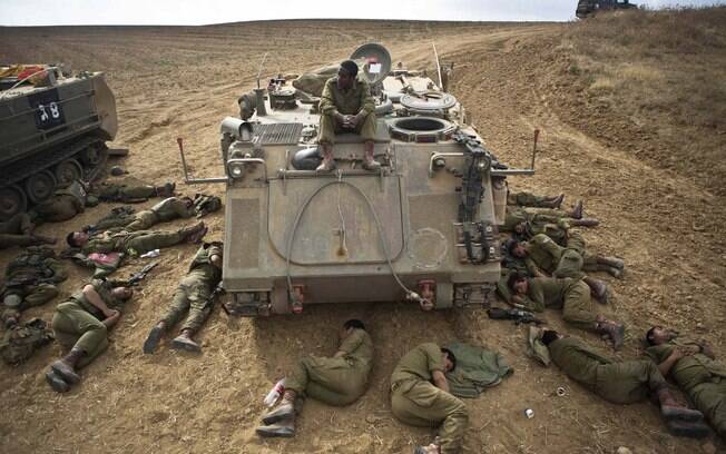 Soldados israelenses dormem no chão ao lado de um veículo blindado fora da Faixa de Gaza (15/7)