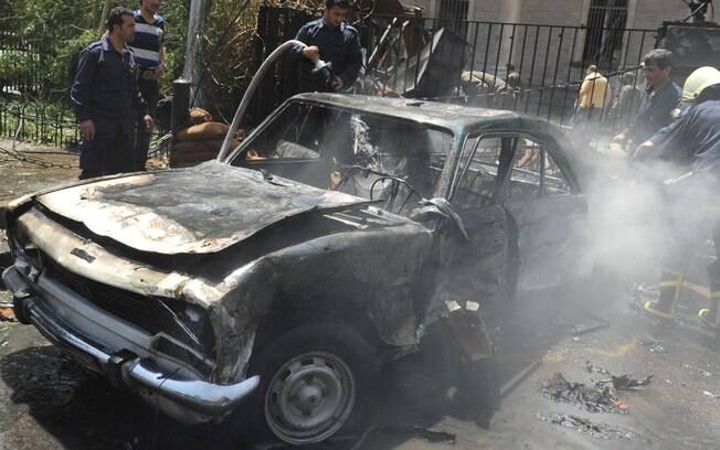 Bombeiros apagam fogo de carro em chamas em cena de explosão no distrito central de Marjeh, Damasco, Síria (30/04)