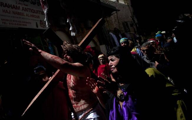Peregrino cristão vestido como Jesus Cristo carrega cruz durante representação da crucificação na Cidade Velha de Jerusalém (29/03)