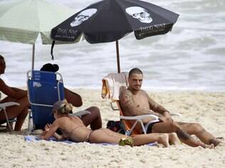 Felipe Titto toma sol na praia da Barra da Tijuca com a mulher