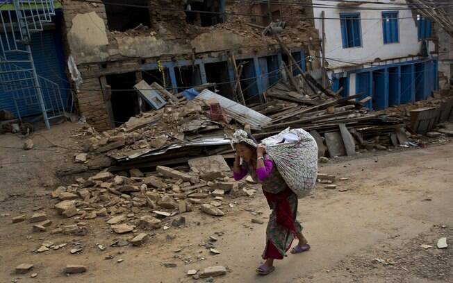 Mulher carrega pertences em cidade do Nepal destruída por dois terremotos em menos de um mês (13.5.2015)