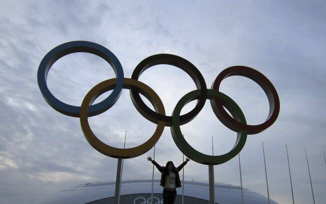 Mulher posa ao lado dos anéis olímpicos em Sochi, na Rússia