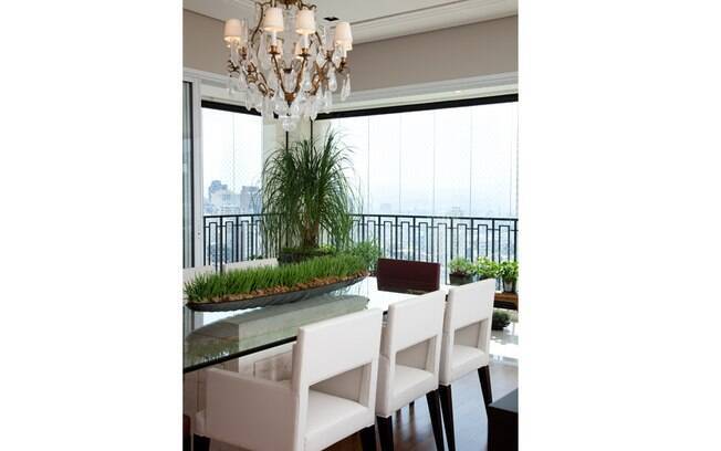 A sala de jantar desse apartamento ganhou maior iluminação natural através da integração com a varanda. As janelas trazem a vista da cidade para dentro da casa