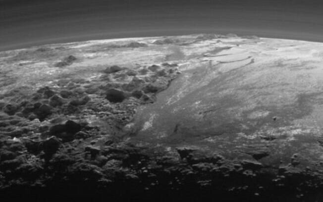Luz solar do fundo destaca camadas da atmosfera de Plutão e terreno diverso