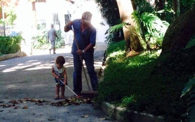 Com uma vassourinha, Dom ajuda a tirar a folhagem da rua