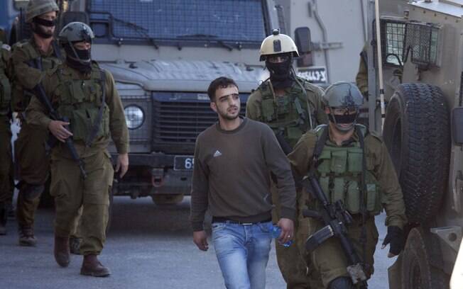 Soldados israelenses prendem palestino na cidade de Hebron, Cisjordânia, durante buscas por adolescentes desaparecidos (14/6)