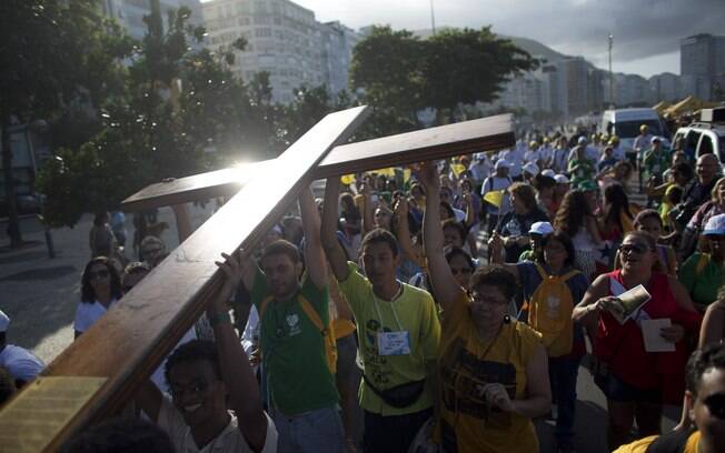 Jovens carregam cruz símbolo da JMJ na praia de Copacabana no domingo (21). Ela foi entregue aos jovens pelo Papa João Paulo II, na edição de 1983 do evento