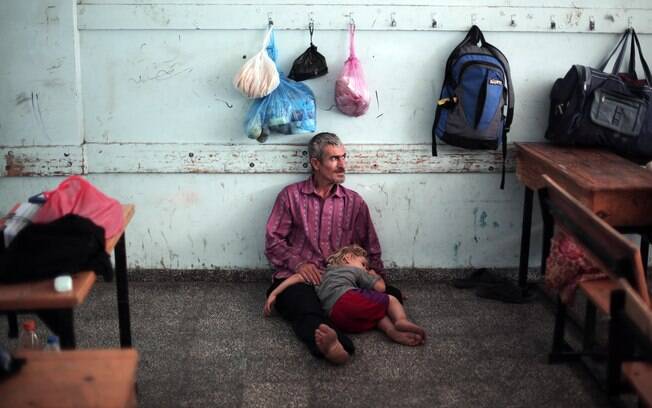 Menina descansa no colo do pai depois de fugir de ataques aéreos israelenses na Faixa de Gaza (14/7)