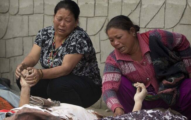 Mulheres choram diante dos corpos de parentes que morreram no terremoto do Nepal