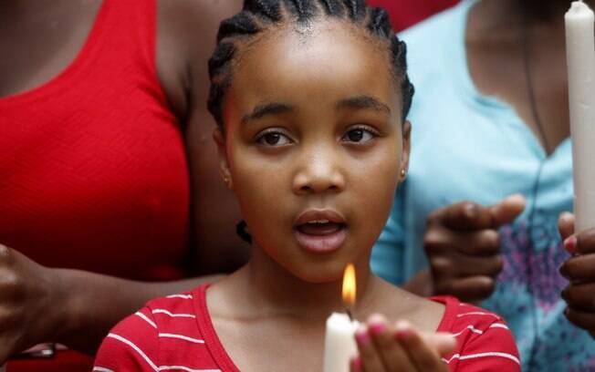 Menina canta e segura vela durante homenagem ao ex-presidente Nelson Mandela, em Johanesburgo (6/12)