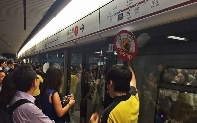 As portas da plataforma do metro com o guarda sinalizando com a placa