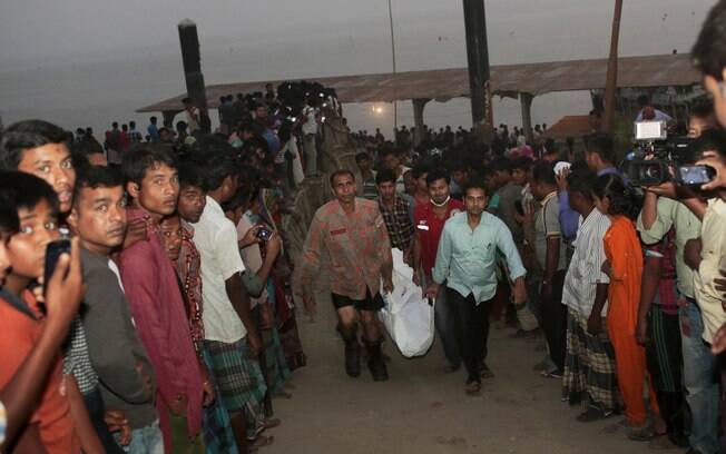 Trabalhadores da equipe de resgate de Bangladesh transportam corpo de uma das vítimas fatais de naufrágio no rio Padma