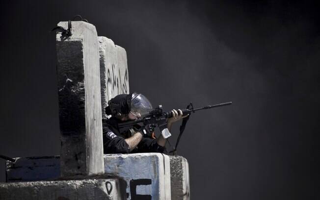 Policial israelense de fronteira mira sua arma durante confrontos com palestinos que protestam na Cisjordânia contra ofensiva na Faixa de Gaza (18/7)