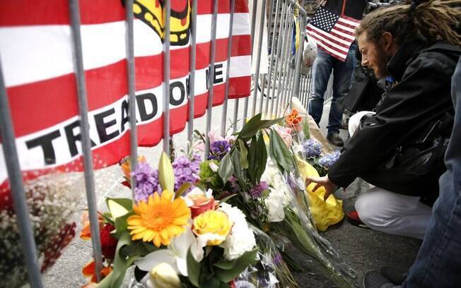 Homem coloca bilhete com flores em barricada de polícia perto da linha de chegada da Maratona de Boston (16/04)