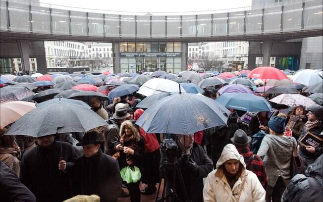 Debaixo de chuva, dezenas de pessoas fizeram um minuto de silêncio no Parlamento Europeu, em Bruxelas na manhã desta quinta (8)