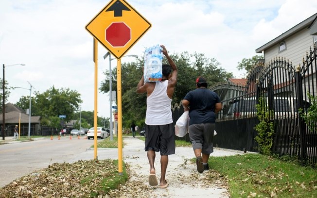 Um homem carrega um galão de água que recebeu em um centro de distribuição em Houston, no Texas, em 11 de julho de 2024